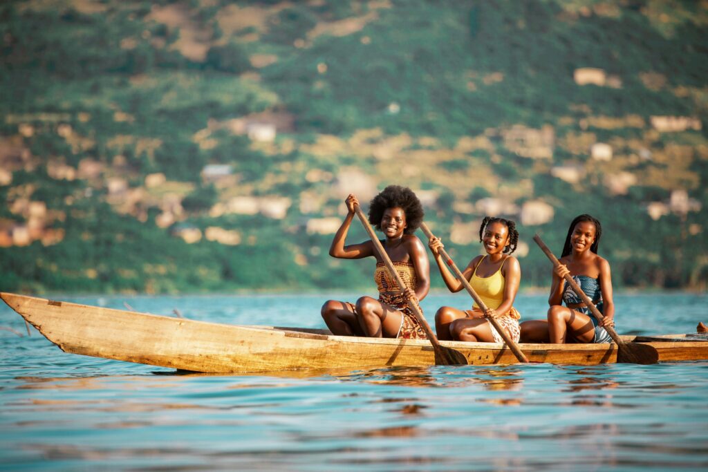 Services Three young women paddling a boat on a serene river in Accra, Ghana.