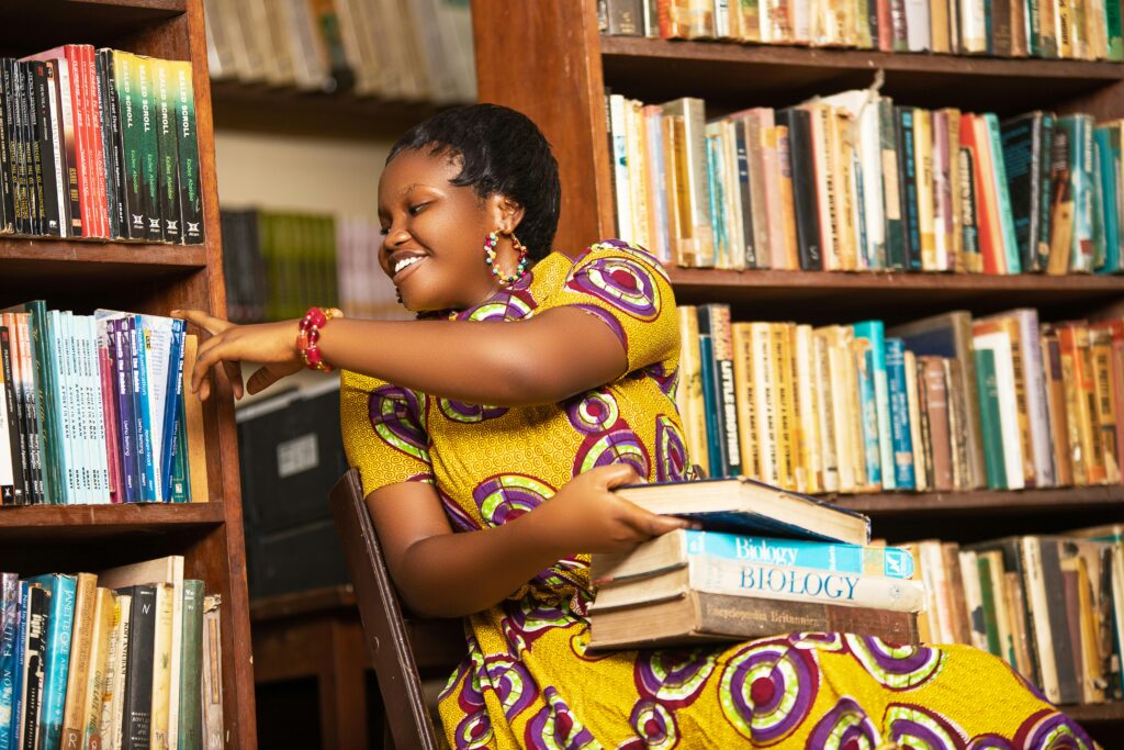 Services Smiling African woman reading books in a Ghana library, showcasing vibrant culture and education.